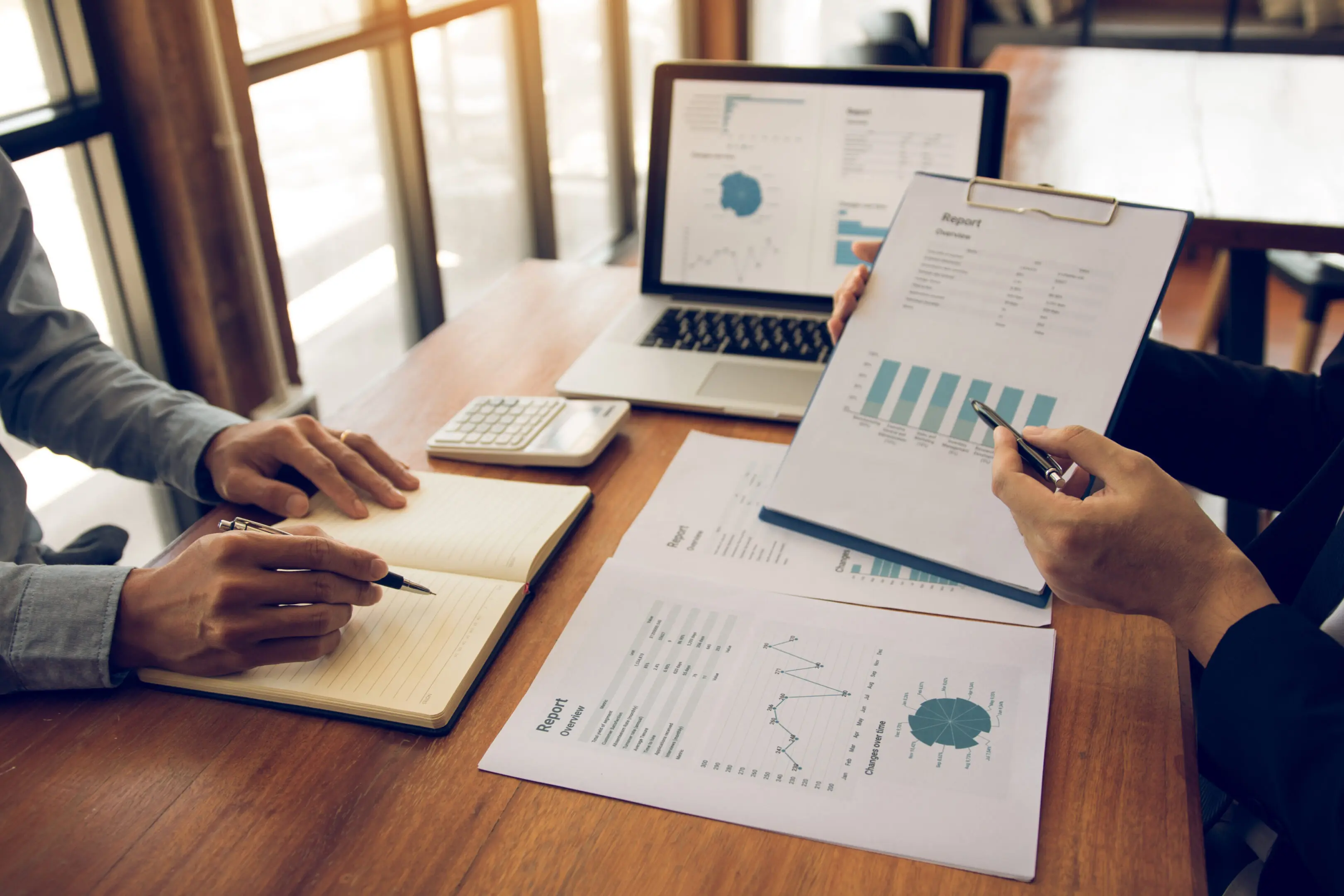 Two people analyzing financial charts and graphs at a desk.