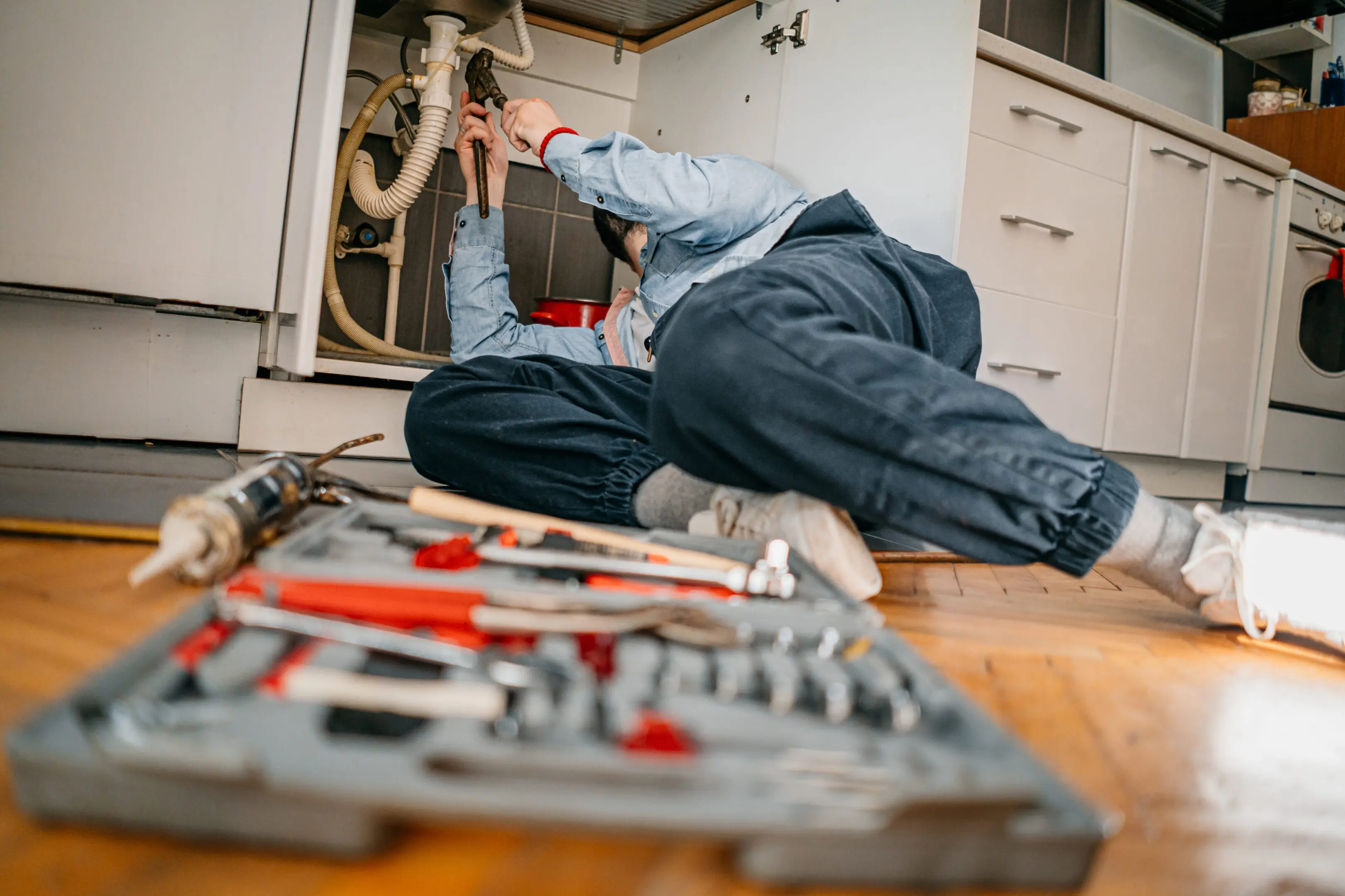 Person repairing an appliance with tools scattered nearby.