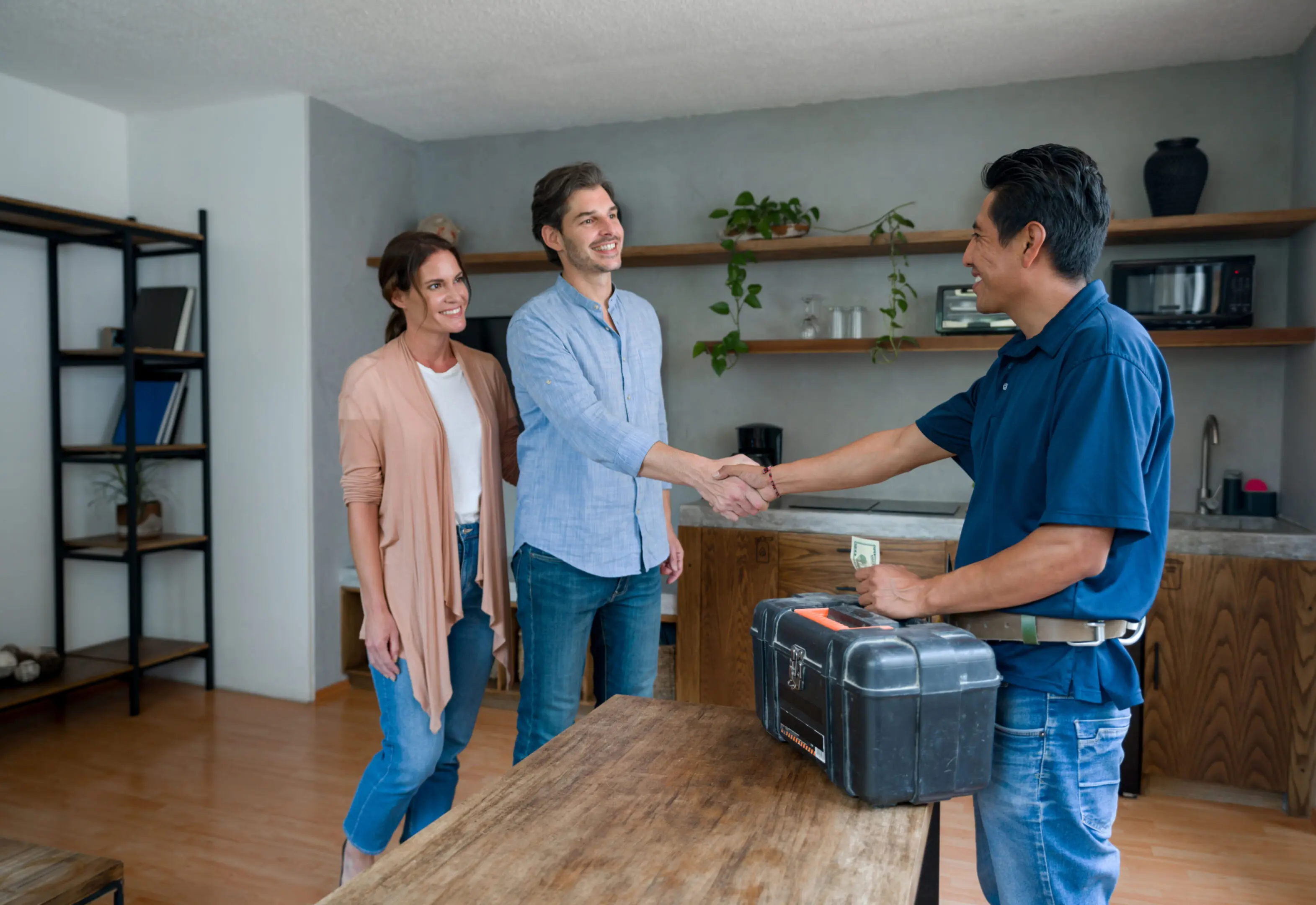 Couple greeting a delivery person with a handshake indoors.