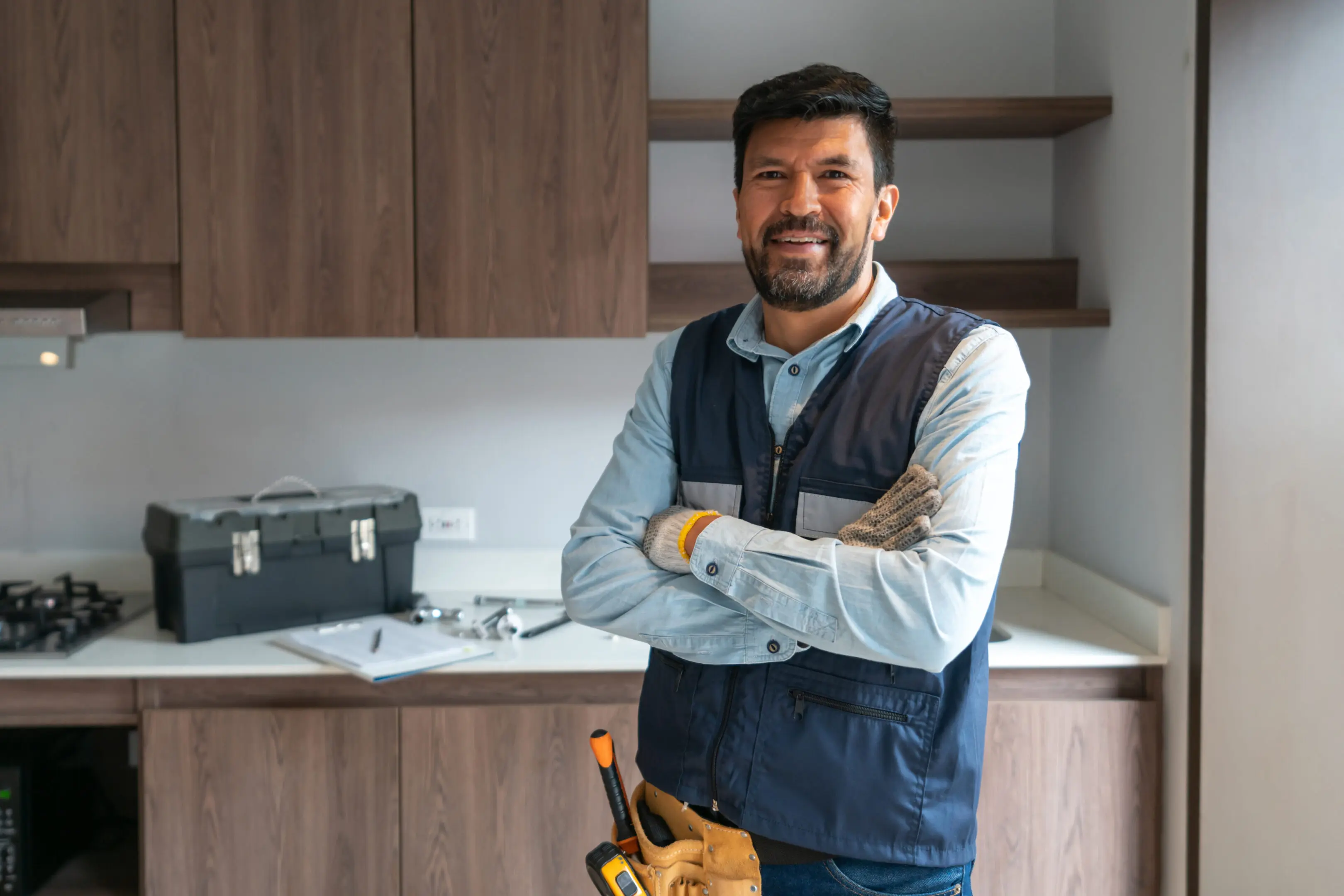 Confident handyman standing in a modern kitchen with tools.