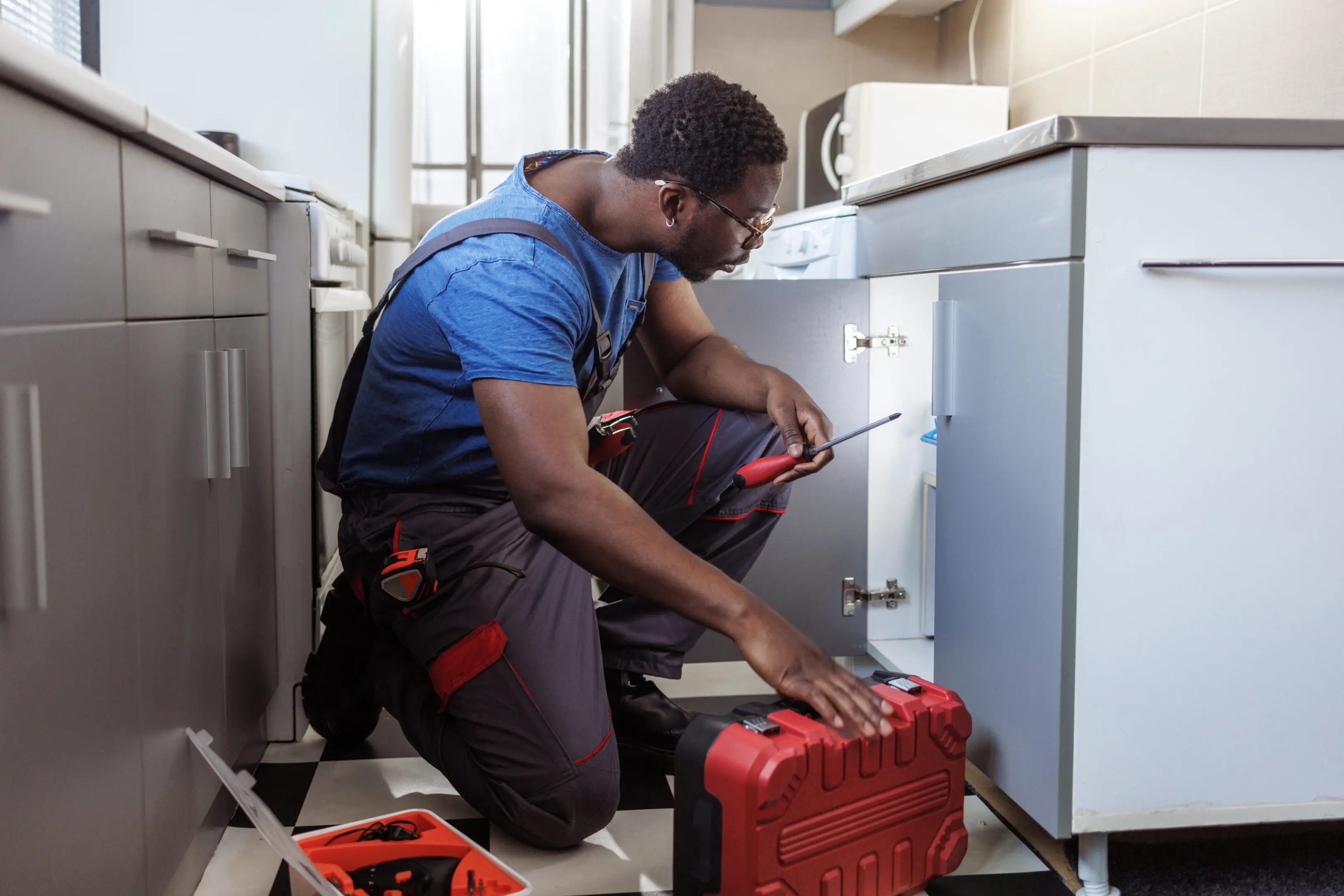 Technician fixing a home appliance with tools.