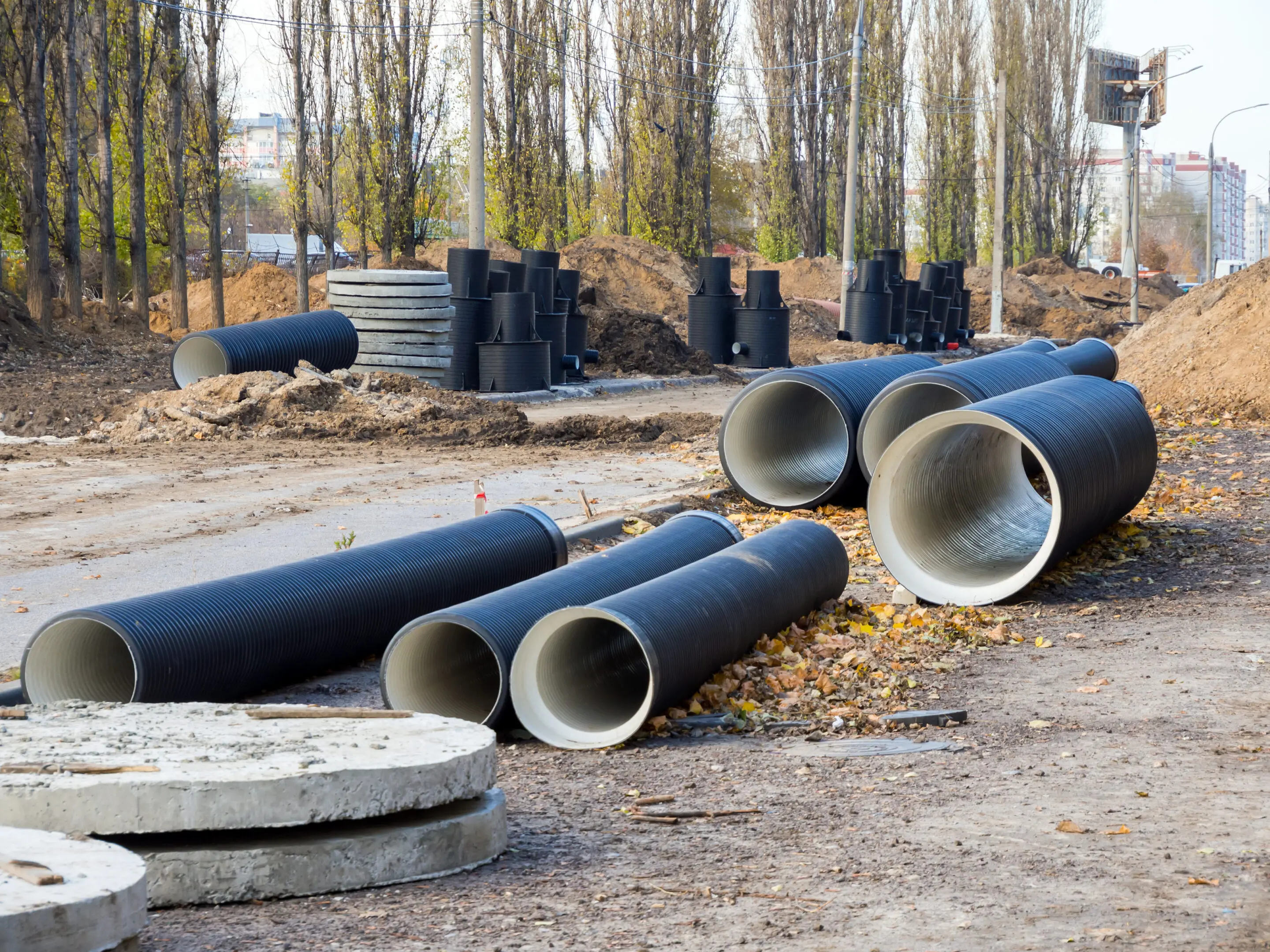 Construction site with large concrete pipes and stacks of tires.