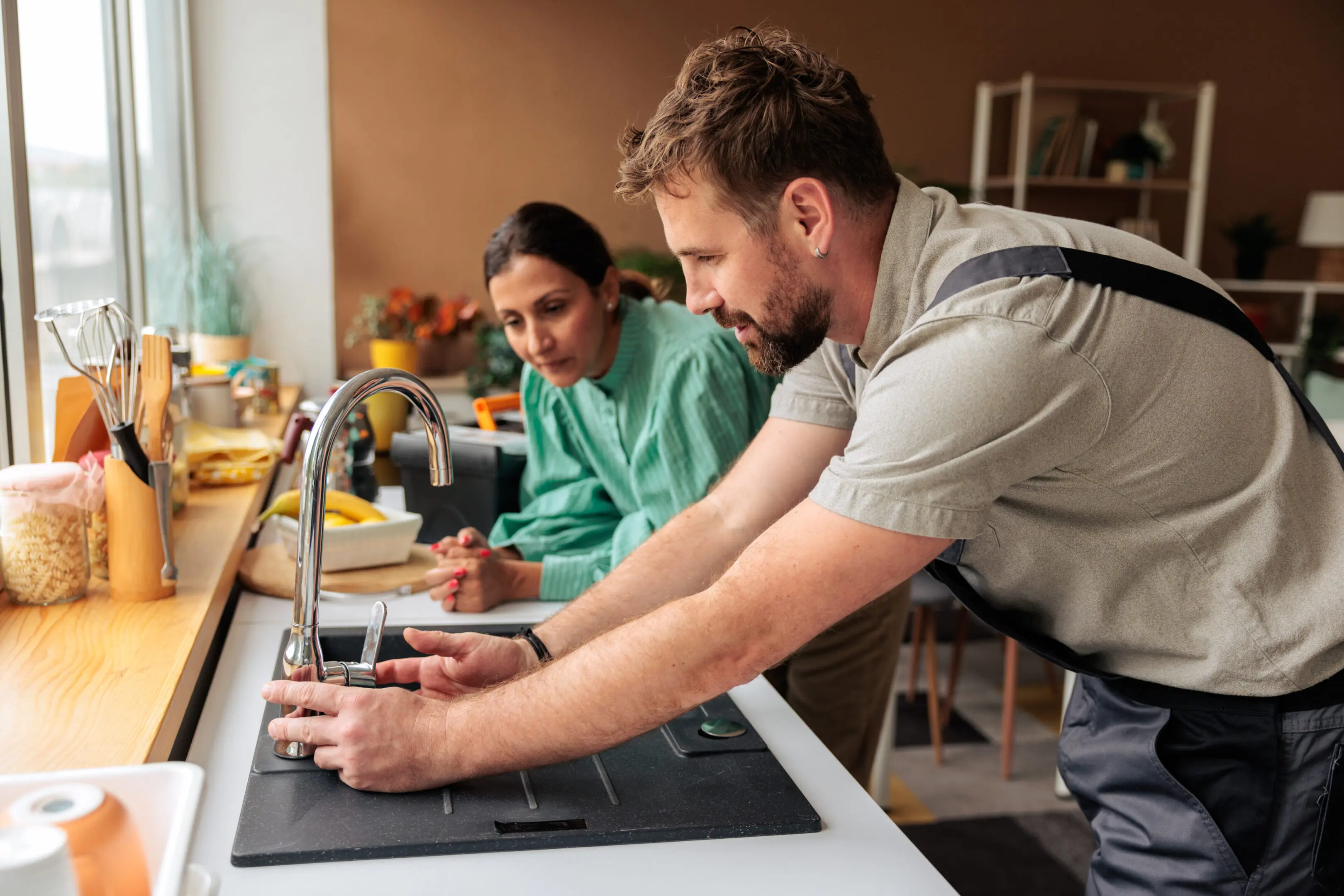 A man and woman working together on a kitchen sink project.