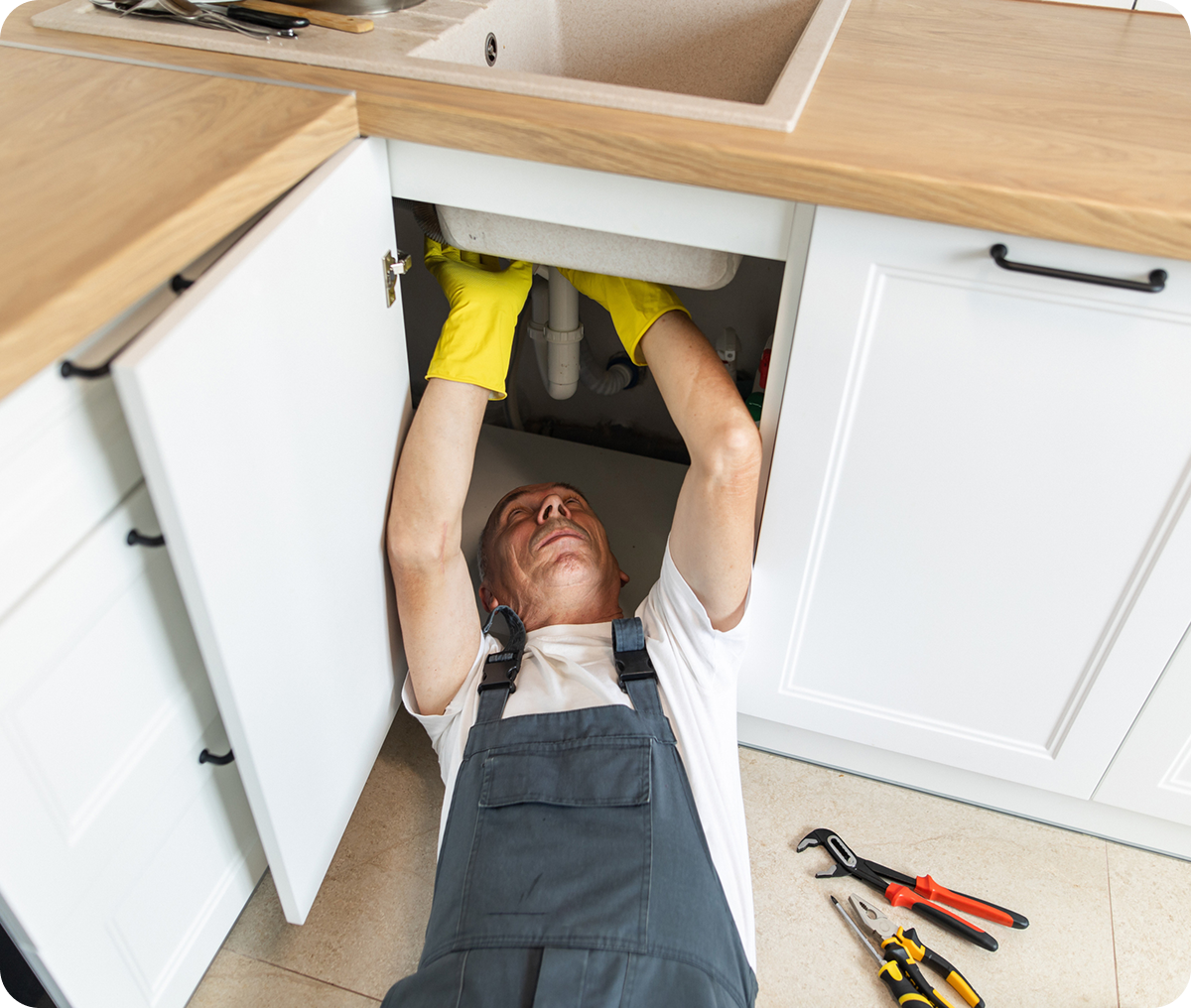 Plumber fixing kitchen sink pipes
