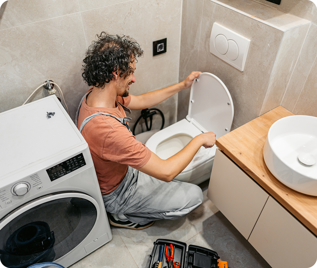 Plumber fixing a toilet in bathroom