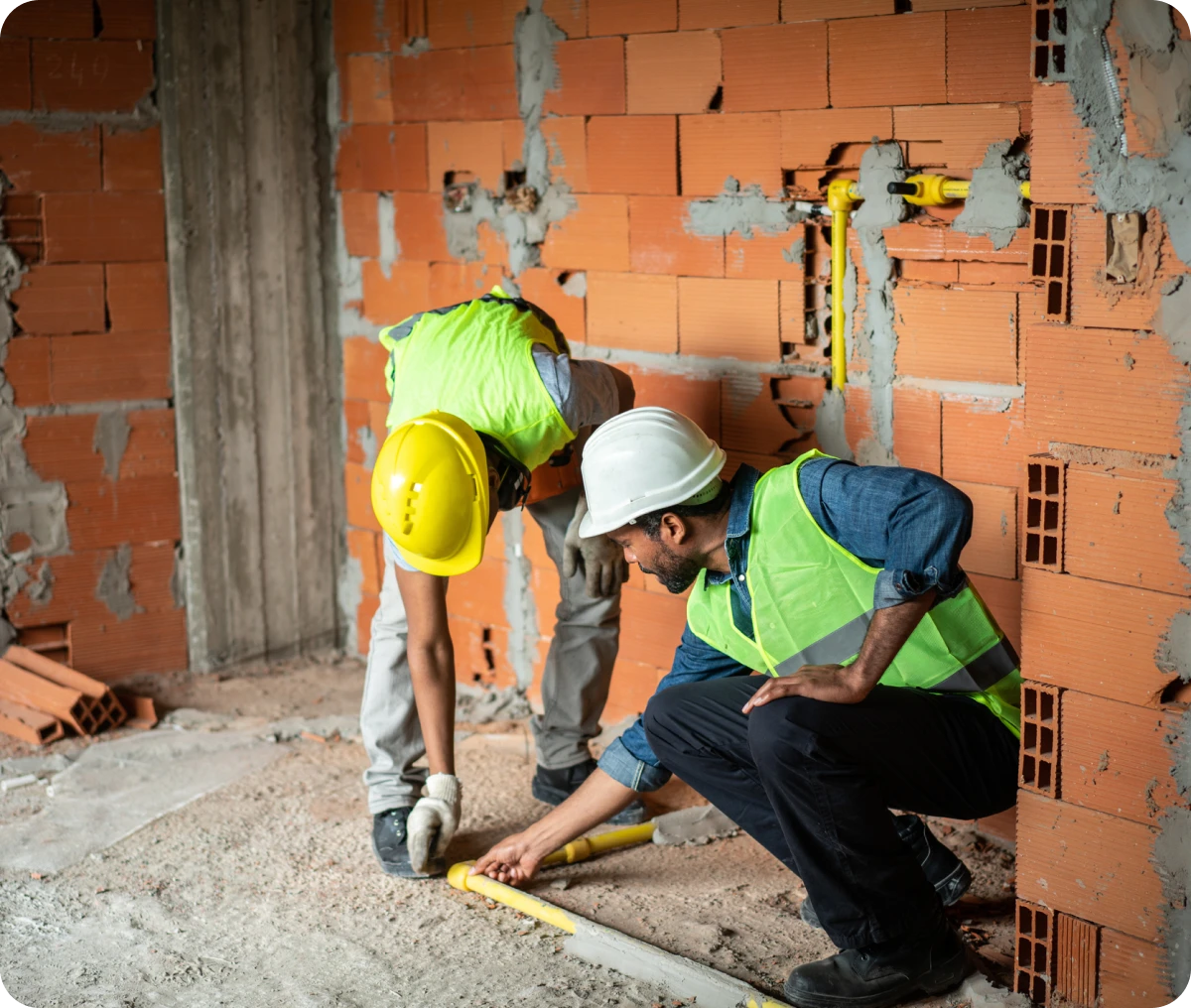 Construction workers measuring pipes on site