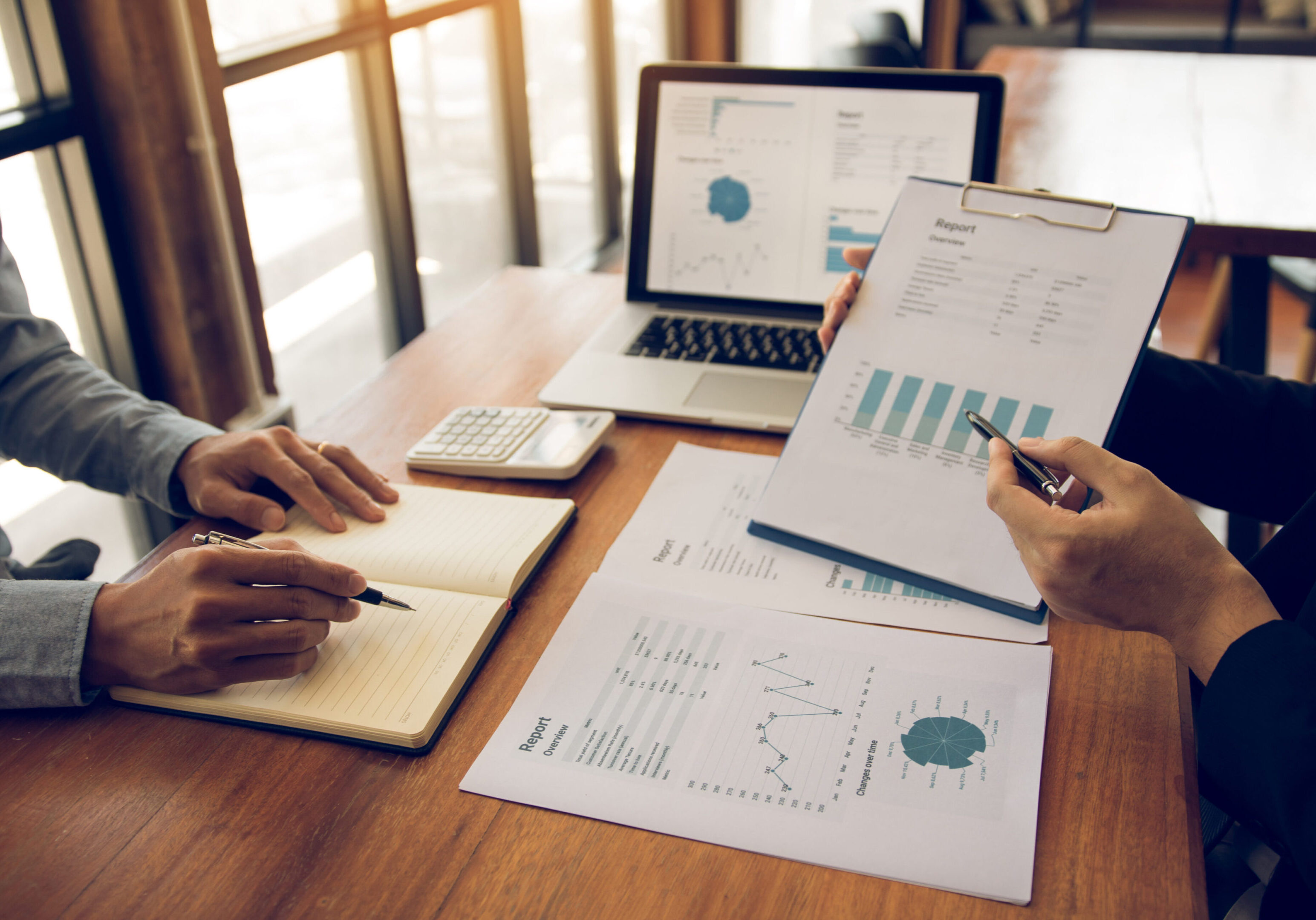 Two people analyzing financial charts and graphs at a desk.