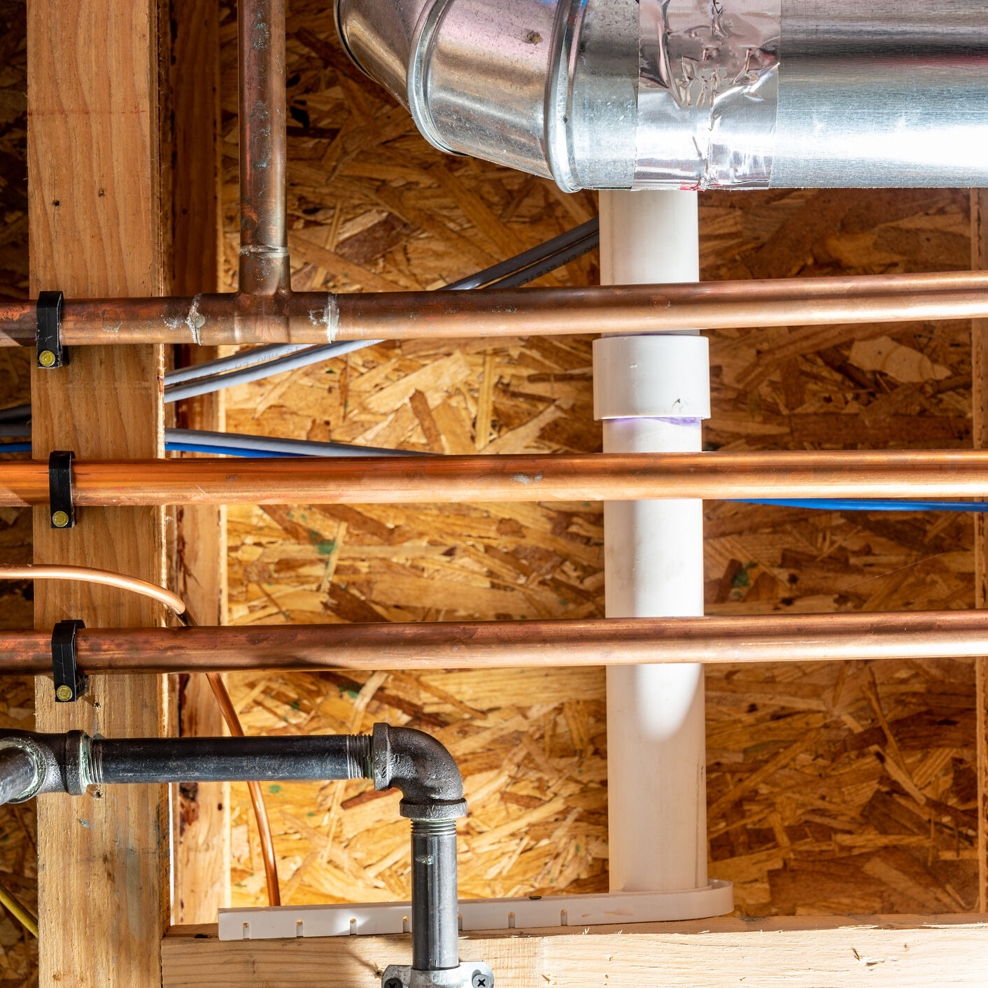 Close-up of copper pipes installed in a wooden ceiling framework.