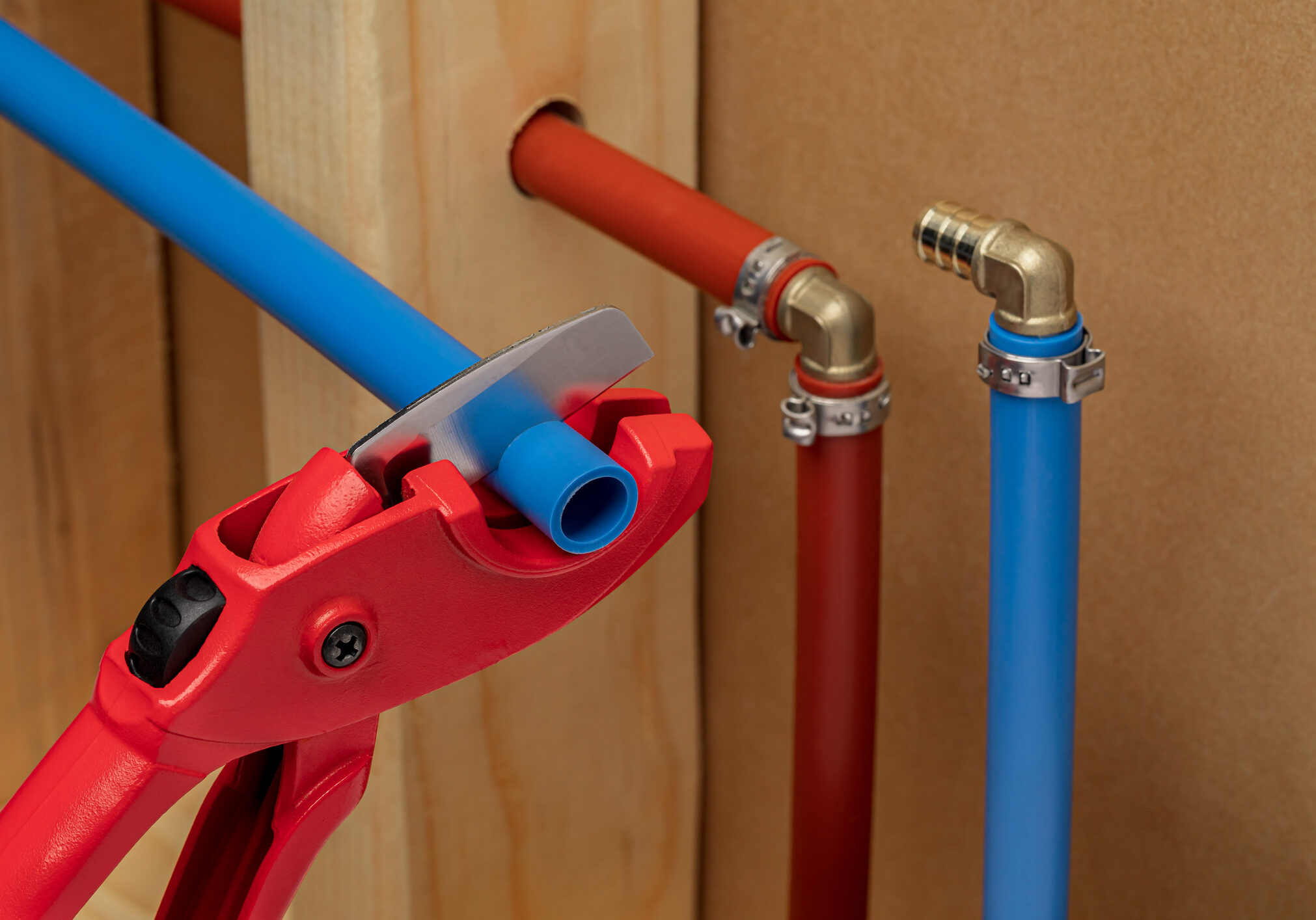 Plumbing pipes with a pipe wrench adjusting a blue pipe fitting.