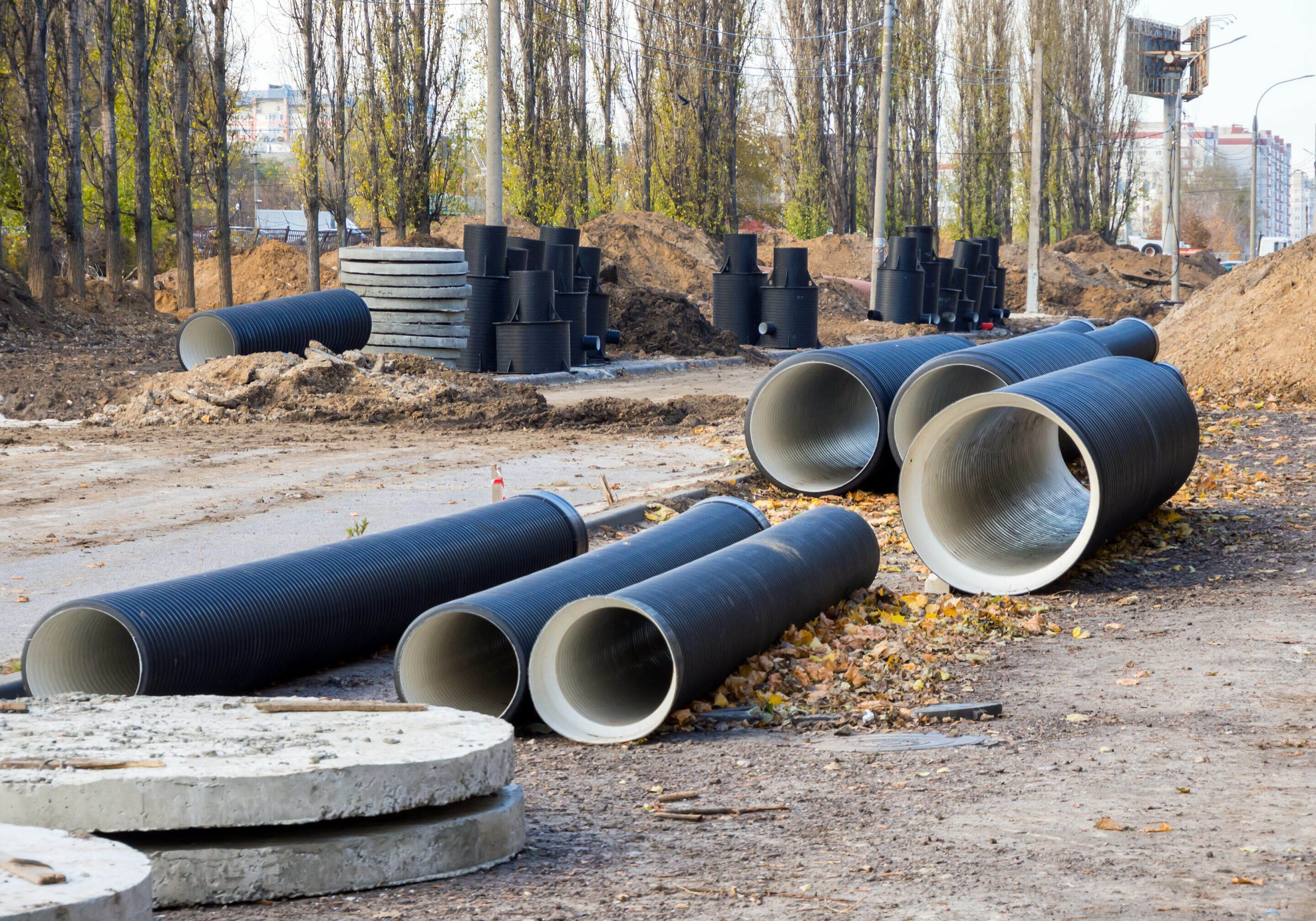 Construction site with large concrete pipes and stacks of tires.