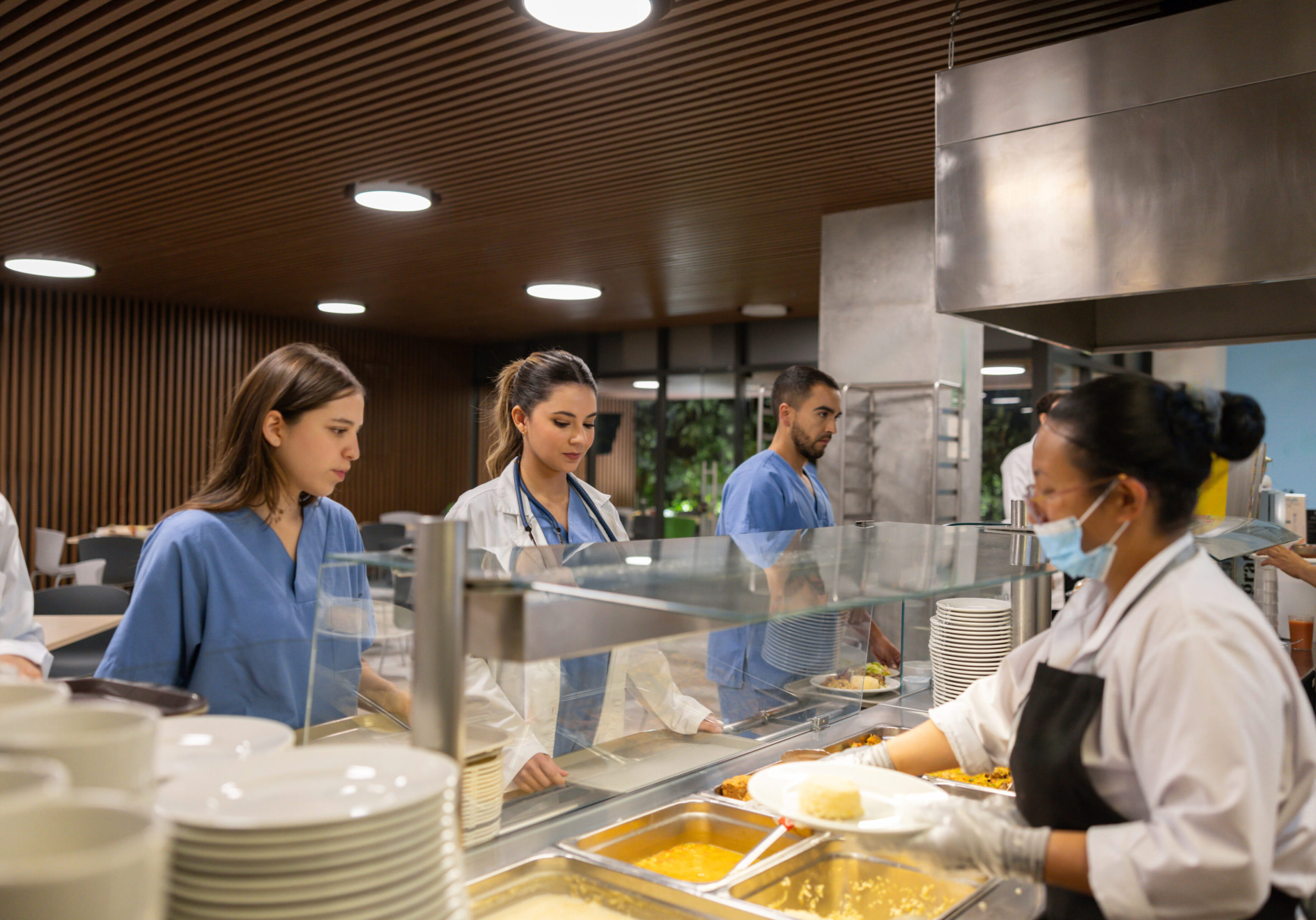 People choosing food from a cafeteria serving line.