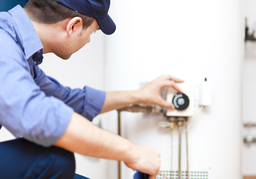 Plumber inspecting water heater controls