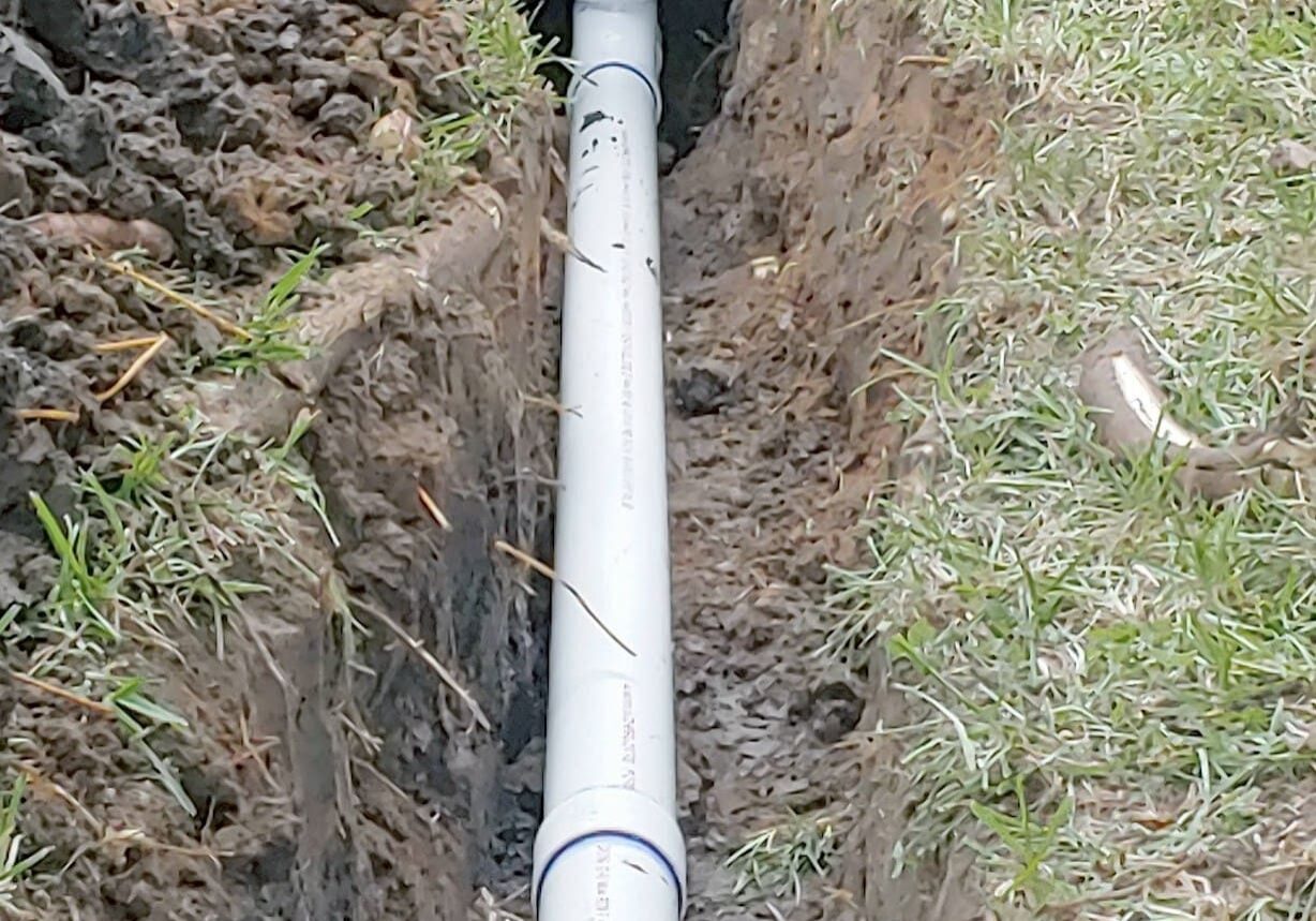 PVC pipe installed in a dirt trench.
